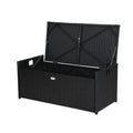Black rattan outdoor storage bench with lid fully open, cross-brace frame and chain restraints visible inside