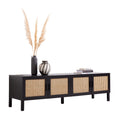 Black rattan TV unit angle view on white pampas grass tall dark vase striped vase and stacked fashion books