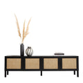 Black rattan TV unit on white with pampas grass dark vase striped vase and stacked fashion books on top