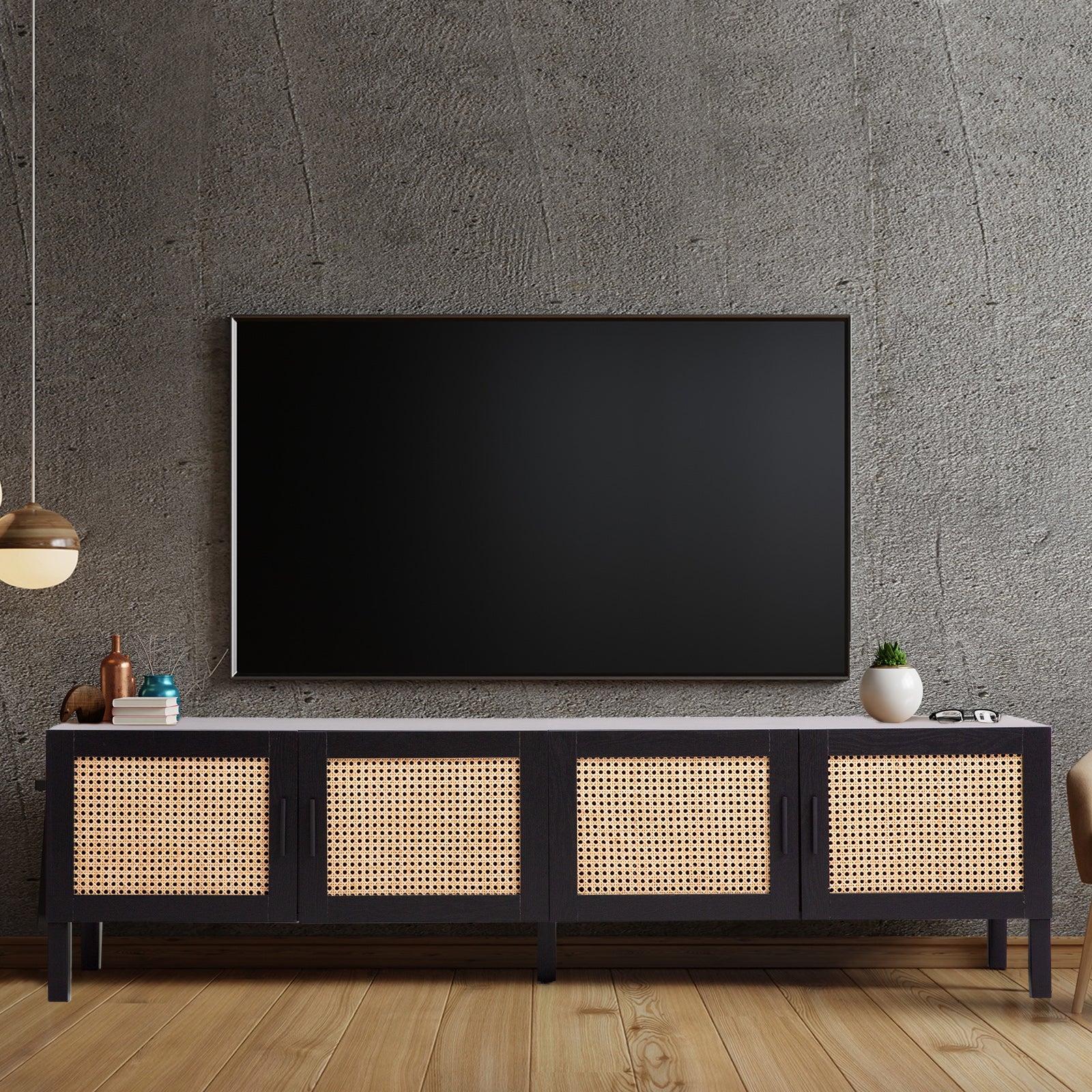 Black rattan TV unit in grey concrete room with wall-mounted TV pendant light copper mug and small plant