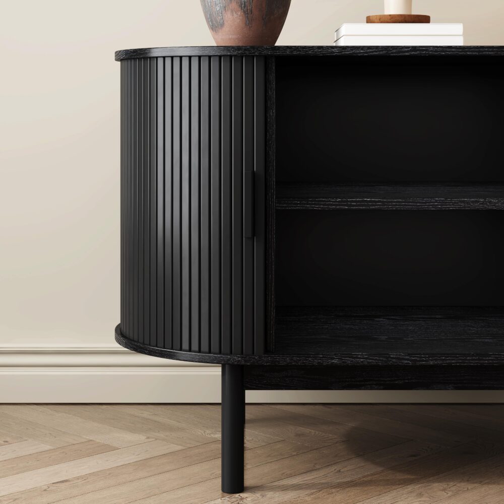 Close-up of black reeded sideboard rounded end panel and open interior with two shelves and tapered leg on herringbone floor