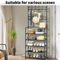 Black shoe and hat stand in living room with curtain and plant loaded with shoes clothes and accessories