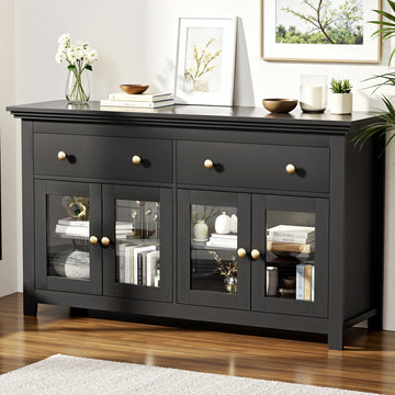 Black sideboard in living room with two drawers and four glass-panel doors with gold knobs, flowers and books on top
