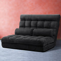 Black charcoal suede floor lounger upright against coral pink wall with tufted seat and built-in backrest bolster