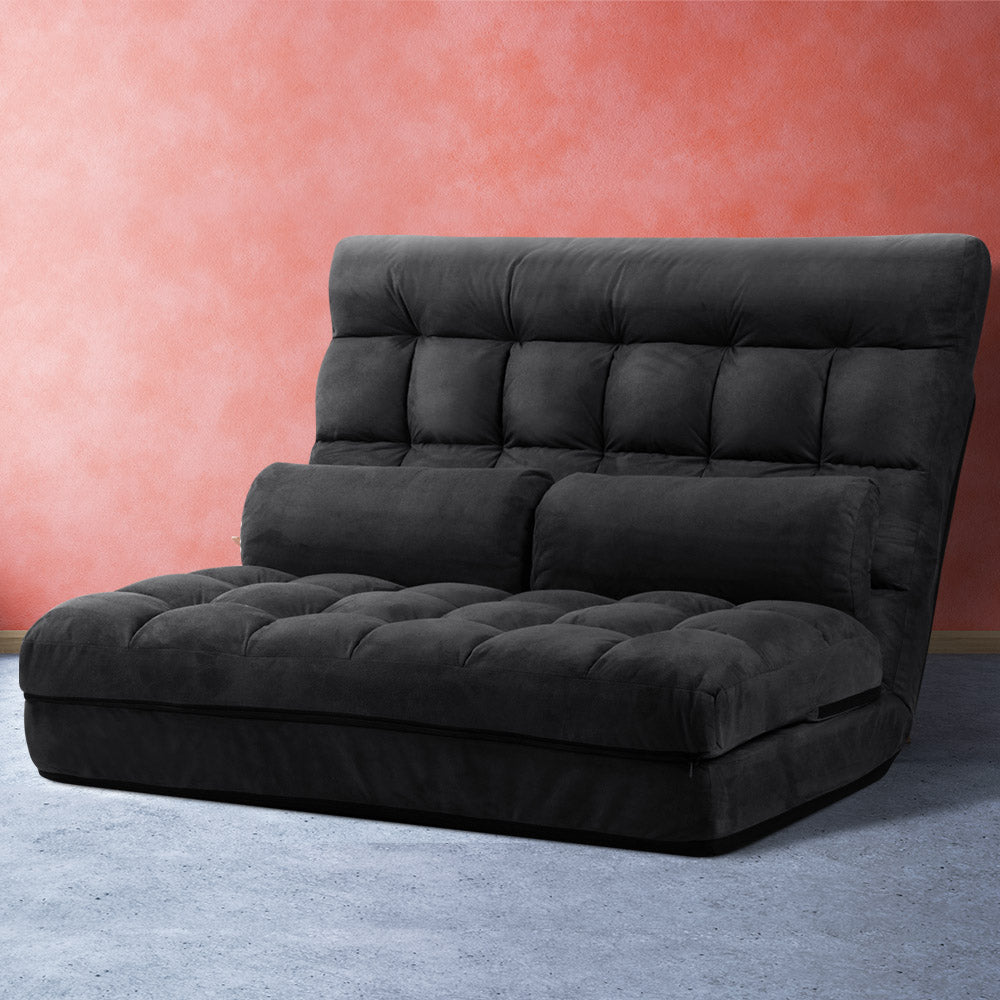 Black charcoal suede floor lounger upright against coral pink wall with tufted seat and built-in backrest bolster