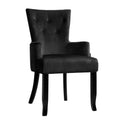 Black velvet wingback armchair with button-tufted high back and black wood legs, angle view on white background