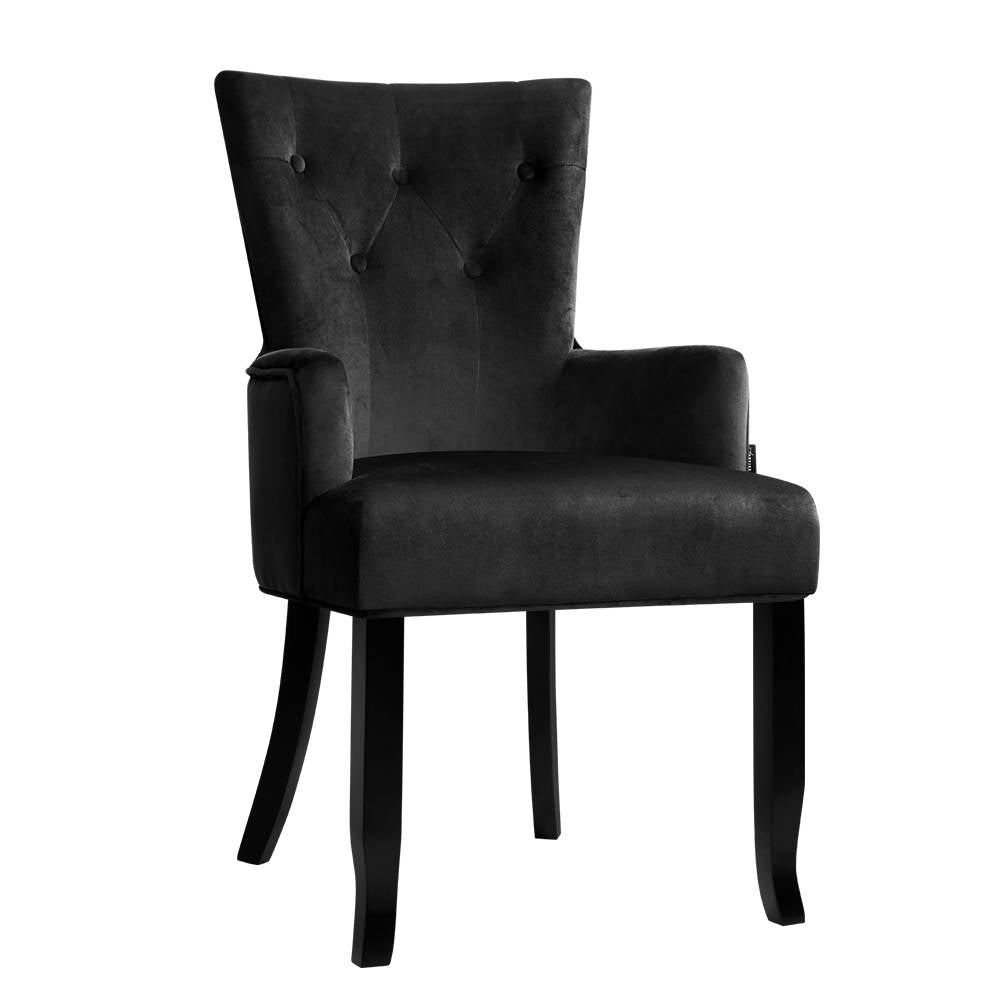 Black velvet wingback armchair with button-tufted high back and black wood legs, angle view on white background