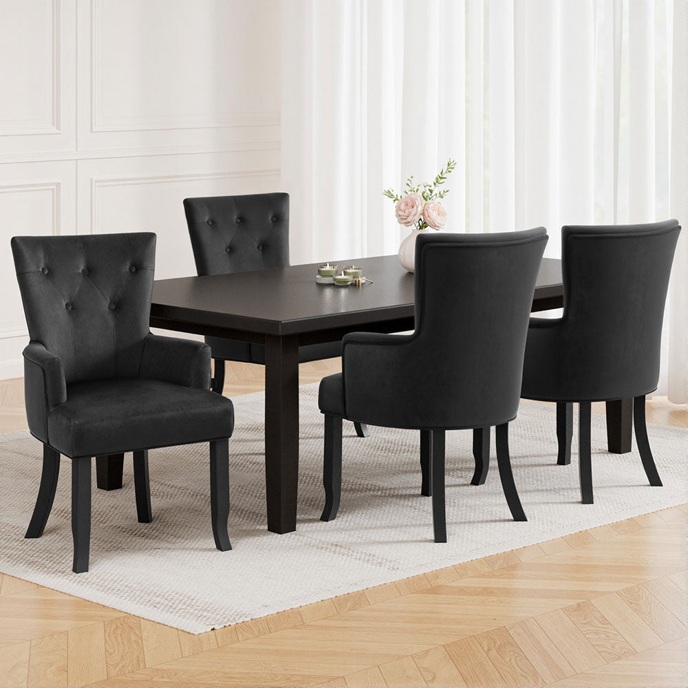 Four black velvet wingback dining chairs around dark espresso dining table in white room, roses in vase and herringbone floor