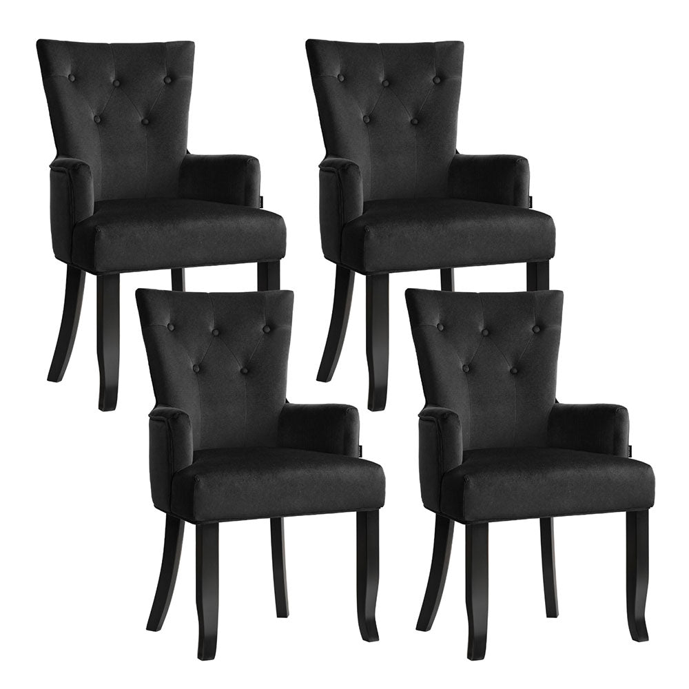 Set of four black velvet button-tufted wingback dining armchairs, two-by-two angle view on white background