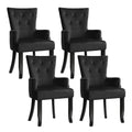 Set of four black velvet button-tufted wingback dining armchairs, two-by-two angle view on white background