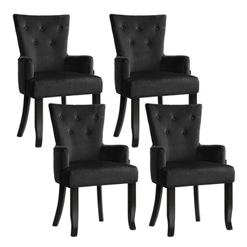 Set of four black velvet button-tufted wingback dining armchairs, two-by-two angle view on white background