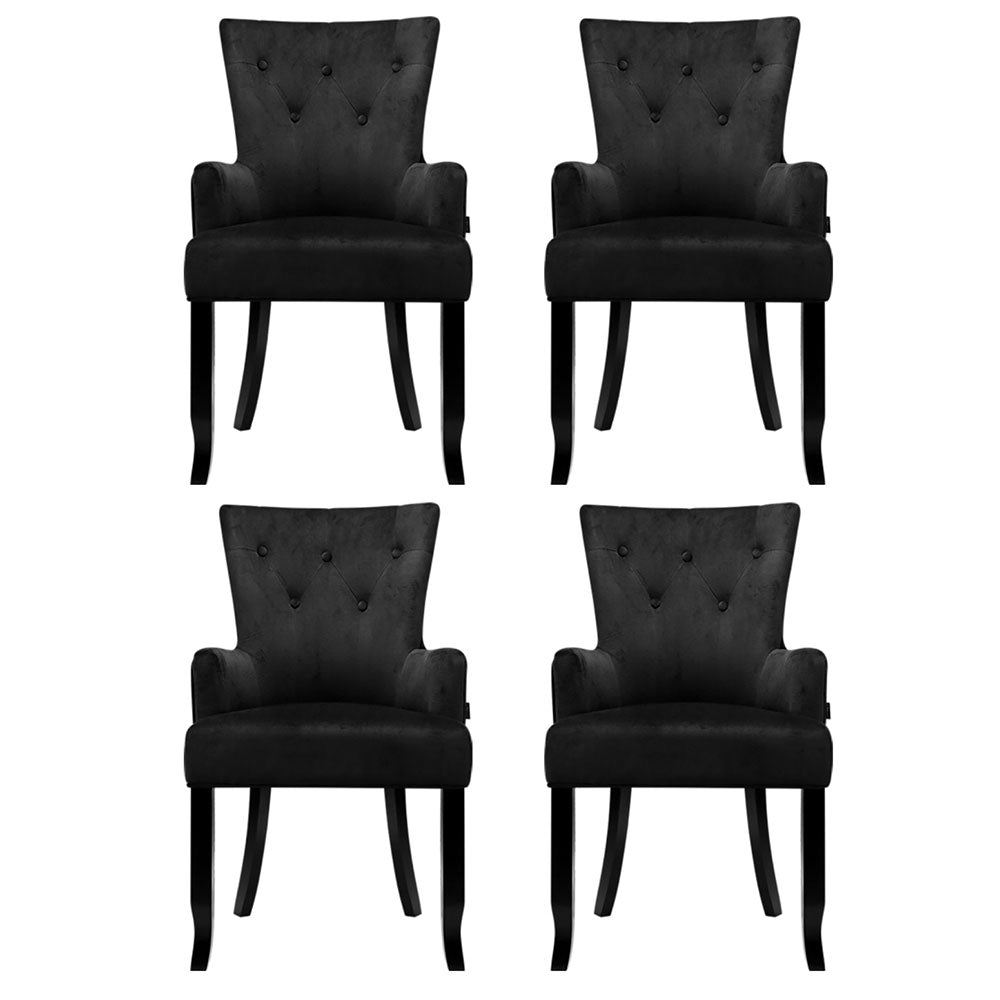 Set of four black velvet button-tufted wingback dining chairs, front view in two-by-two grid on white background