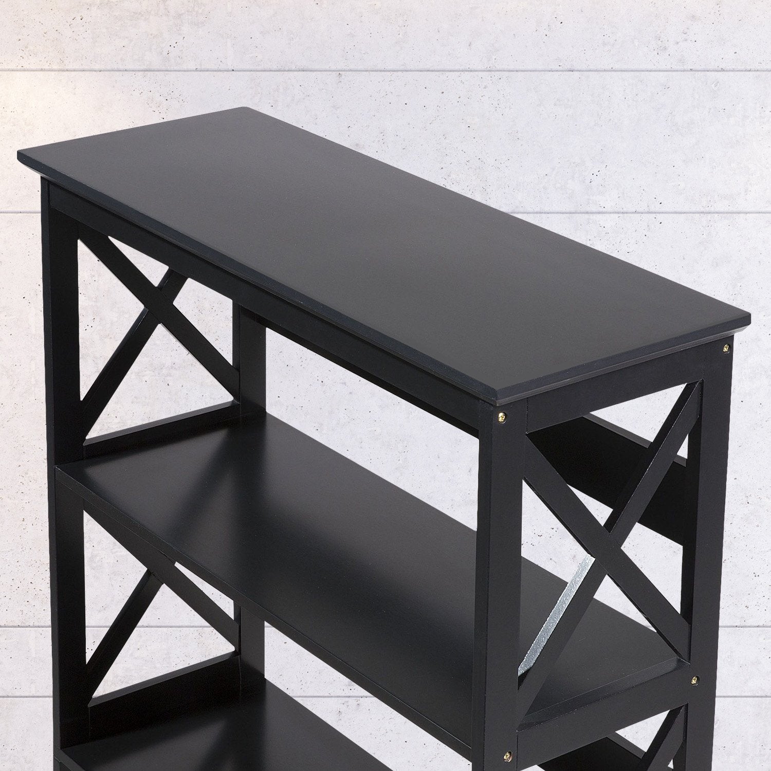 Close-up top-angle view of black X-frame bookshelf showing flat top surface, X-panels and upper shelves against concrete wall