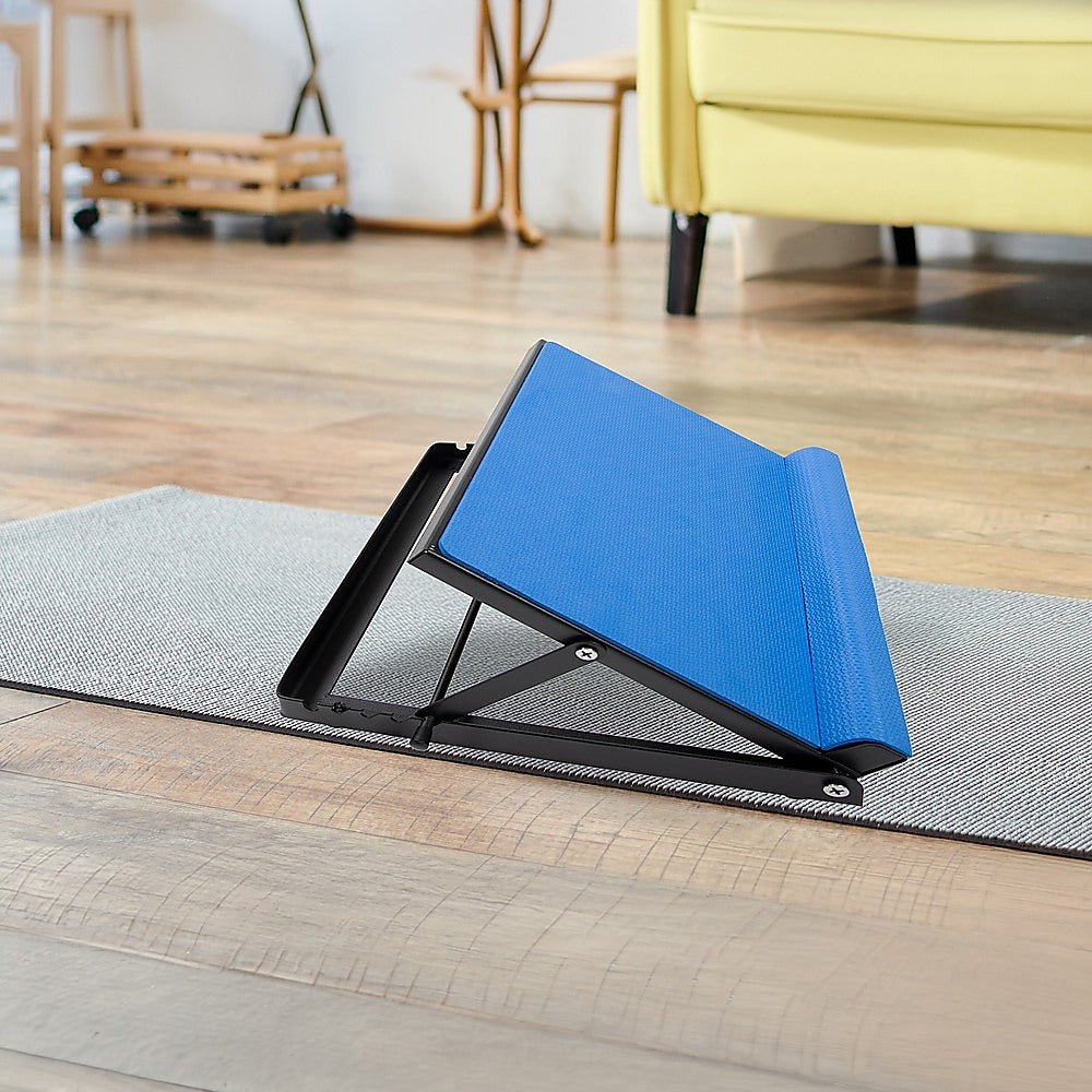 Blue adjustable calf stretching board placed on grey yoga mat on wooden floor in home lifestyle setting