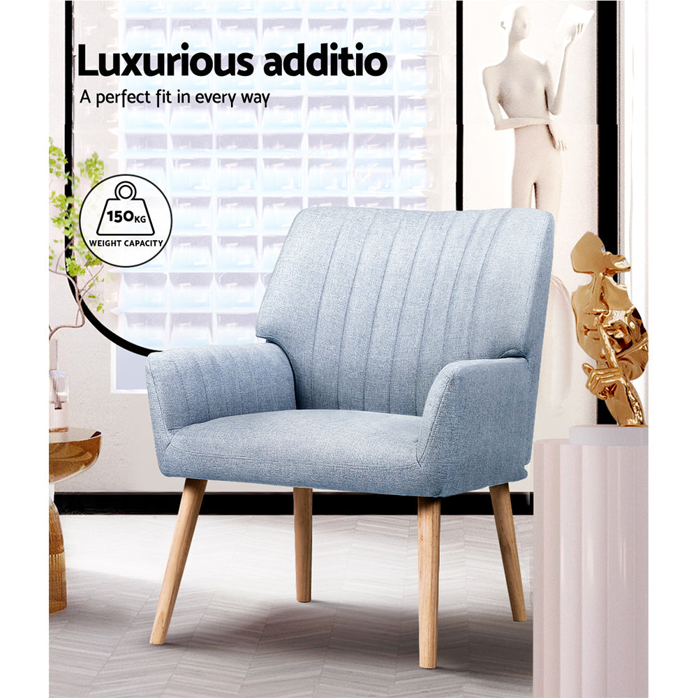 Light blue grey fabric armchair in modern room, 150kg weight capacity badge visible, large window background, gold sculpture