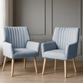 Pair of light blue grey channel-stitched fabric armchairs on timber floor, grey panelled wall background