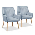 Pair of light blue grey fabric armchairs with vertical channel-stitched backrest and natural wood legs, white background