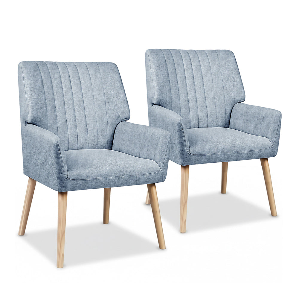 Pair of light blue grey fabric armchairs with vertical channel-stitched backrest and natural wood legs, white background