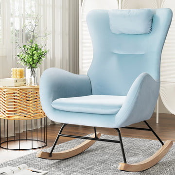 Light blue velvet wingback rocking chair with headrest pillow and wood runners, lifestyle shot with wicker table and plant
