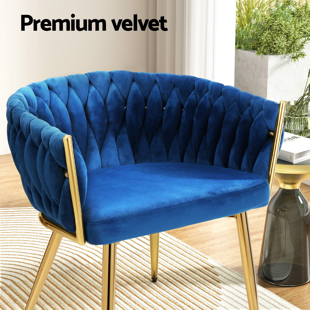 Blue velvet woven back accent chair with gold legs, "Premium velvet" text, side table with glass vase in room setting