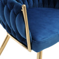 Close-up of blue velvet woven chair back and gold metal armrest bar connecting to padded blue velvet seat