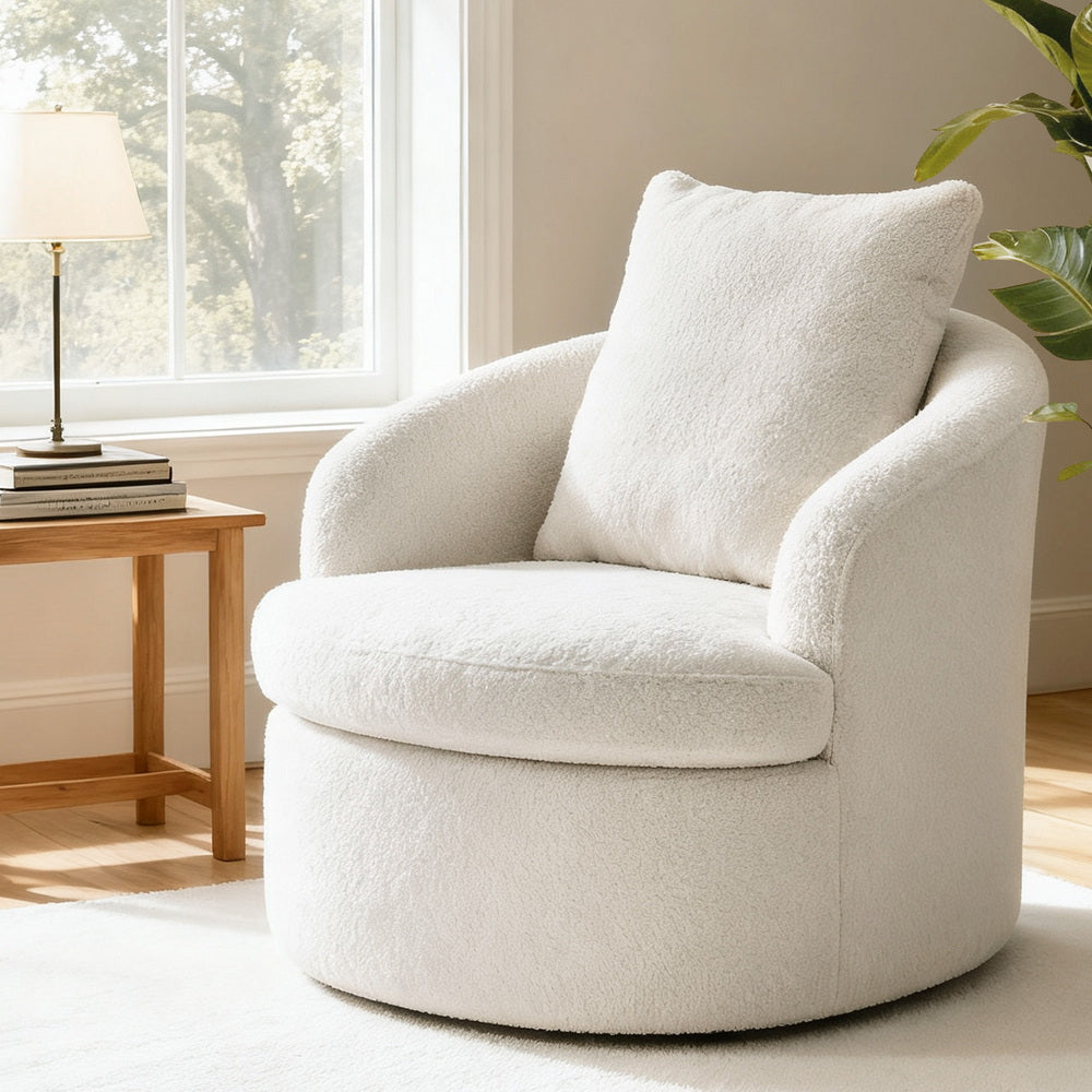 White boucle swivel barrel chair with back cushion in sunlit room with side table and lamp