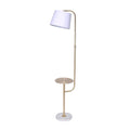 Floor lamp with curved brass arc arm, white tapered shade, round brass side table, and white marble base on white background