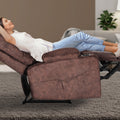 Woman lying fully reclined in brown fabric tufted recliner with footrest extended and cup holder, living room with grey rug