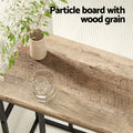 Close-up of a wood grain particle board table top with a glass and small vase styled on the surface.