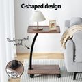 C-shaped side table features: powder-coated metal post and stable screw fixings, lamp on top, grey sofa behind