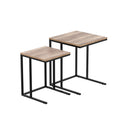 Two C-shaped nesting side tables with wood-grain particleboard tops and black metal frames, white background, different