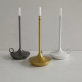 Three candle-style LED lamps in dark grey, gold and white displayed together on white surface, grey background