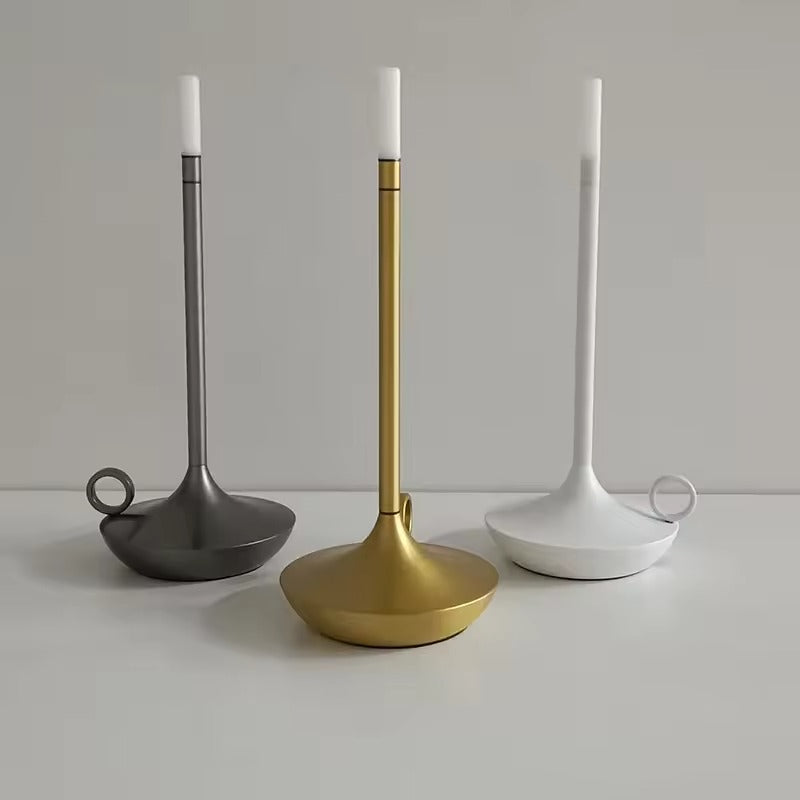 Three candle-style LED lamps in dark grey, gold and white displayed together on white surface, grey background