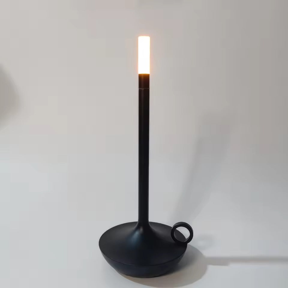 Matte black candle-style LED table lamp with ring handle on round base, warm white glow at top, white background