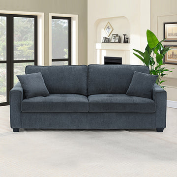Charcoal blue 3-seater sofa with two scatter cushions in living room with large windows and plant