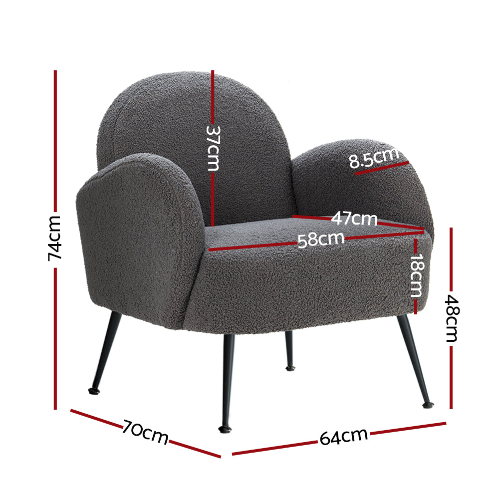 Charcoal grey boucle armchair with rounded cloud-shaped back, curved armrests and black metal tapered legs, angle view