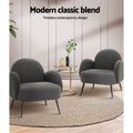 Two charcoal boucle armchairs facing each other with gold side table on jute rug, 