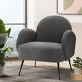 Charcoal boucle armchair near window with mountain view, tropical plant and abstract wall art in living room