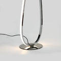 Close-up of chrome lower loop and base on grey background with warm LED glow, black power cord visible