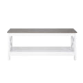 Rectangular coffee table with grey wood-look top and white X-frame base with lower shelf on white background