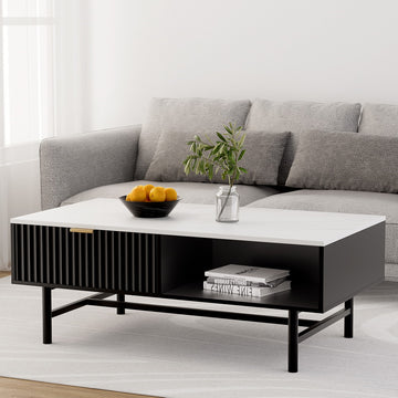 White marble-top coffee table with black ribbed sliding drawer and open shelf, styled with oranges in a bowl and a plant