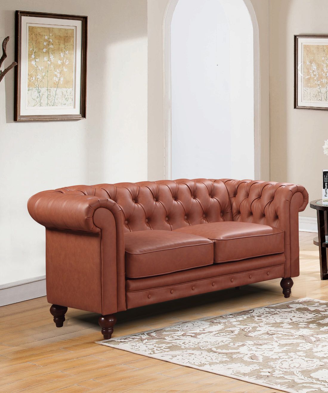 Tan cognac Chesterfield 2-seat sofa in classic room with arched window, rugs and framed prints on wall