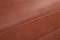 Tan cognac PU leather sofa seat surface close-up showing smooth leather grain with horizontal seam detail