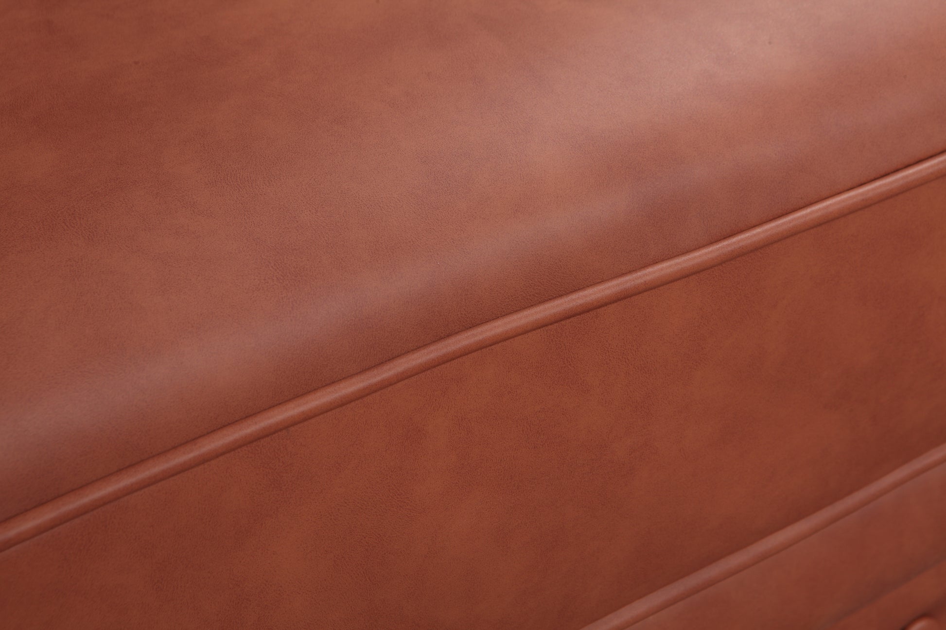 Tan cognac PU leather sofa seat surface close-up showing smooth leather grain with horizontal seam detail