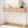 Console table with fluted oak drawer front, white X-frame metal legs, styled with books and green glass vase in room