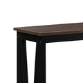 Close-up of dark walnut-effect tabletop corner showing wood grain texture and black frame junction with screws