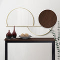 Walnut-top black X-frame console table with dark vases and rattan bowls on top, gold circle mirror on wall behind