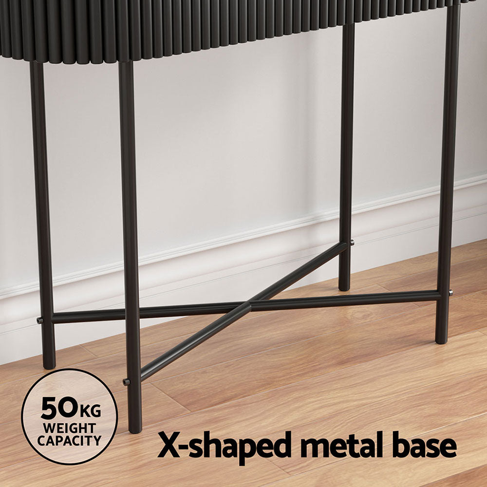 Close-up of black X-shaped metal base with 50kg weight capacity badge, in room with hardwood floor