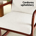 Close-up of beige corduroy seat cushion and walnut armrests with text 