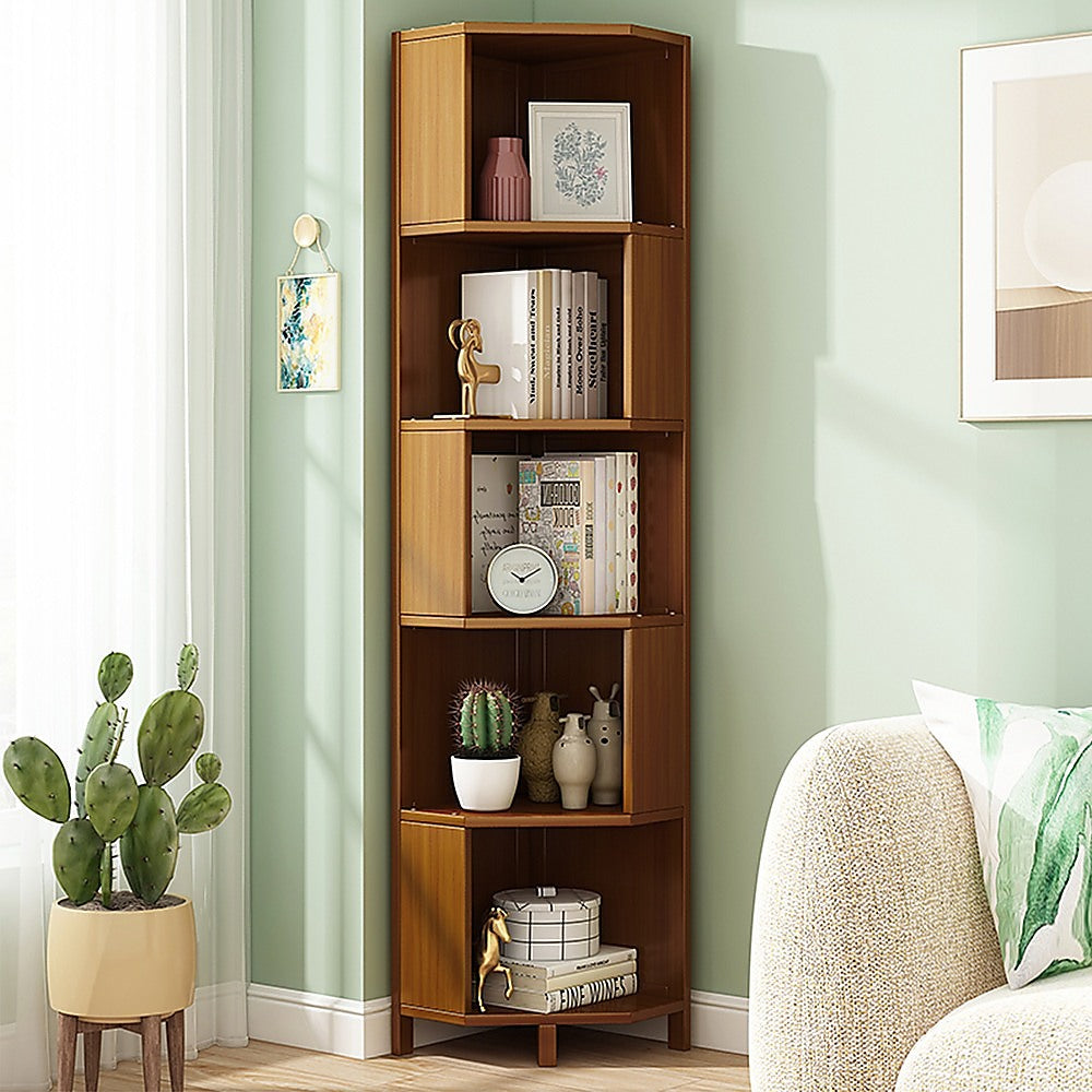 Five-tier corner bookcase in warm brown wood styled with books, plants, and ceramics, front view on white background
